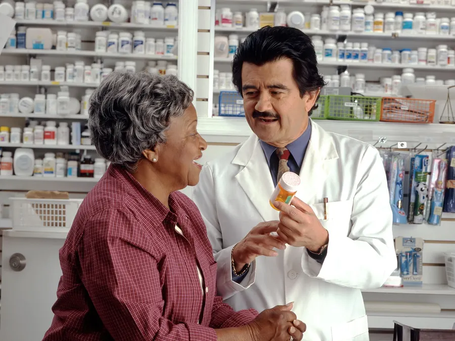 Pharmacist handing a prescription to a patient at the pharmacy counter